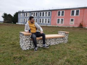Homme décontracté assis sur un banc sans dossier en gabion